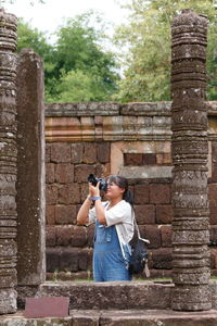 Girl photographing through camera against wall