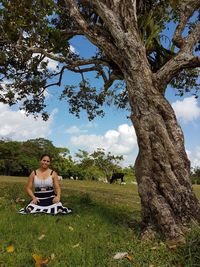 Full length of man sitting on tree trunk