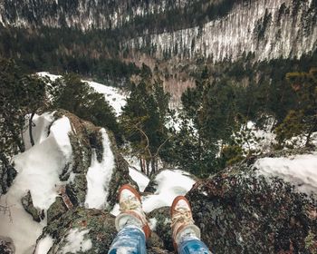 Low section of man standing on snow covered mountain