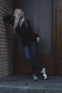 Young woman standing against wall at home