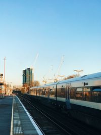 Train at railroad station against clear blue sky