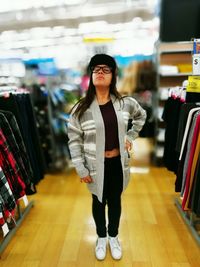 Young woman standing amidst clothes rack at clothing store