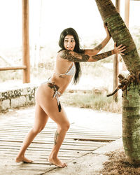 Woman in bikini pulling tree trunk