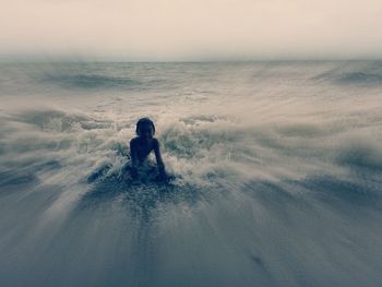 Man in sea against sky