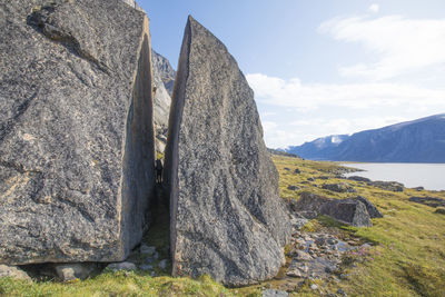 Backpacker squeezes through split in giant cracked boulder.