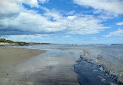 Scenic view of beach against cloudy sky