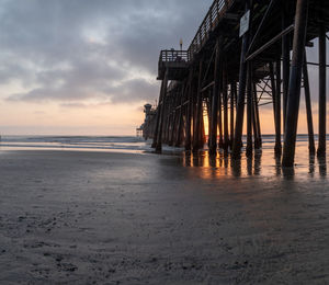 Pier over sea against sky at sunset