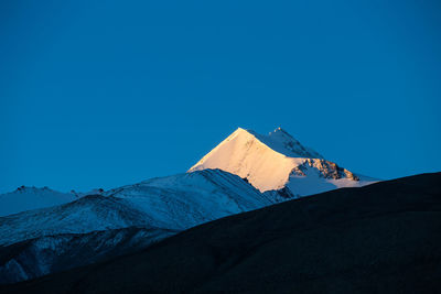 Scenic view of snowcapped mountains against clear blue sky