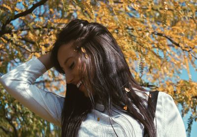 Smiling woman standing against tree