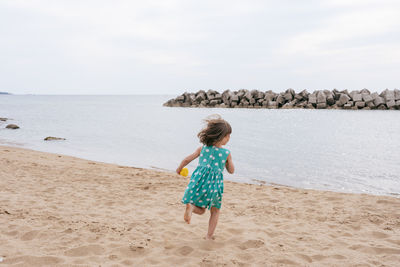 Small girl in a dress. running at the beach