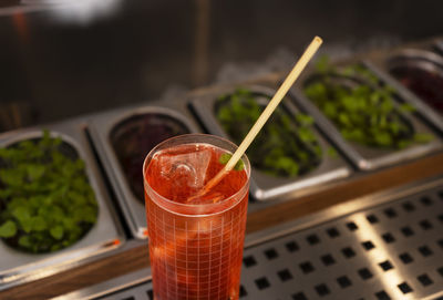 A glass of delicious red alcohol drink with a cocktail tube on a bar counter. night club drink.