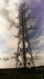 Low angle view of electricity pylon on field