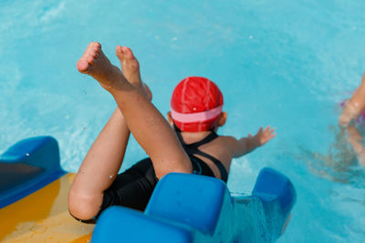 High angle view of girl moving down from slide in swimming pool