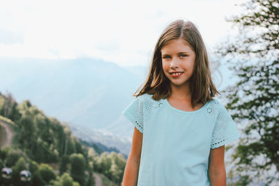 Portrait of smiling girl standing against mountains