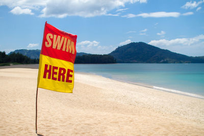 Information sign on beach against sky