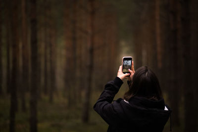 Young woman using mobile phone in the pine forest