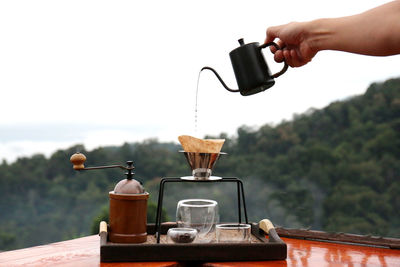 Cropped hand of man holding coffee against clear sky