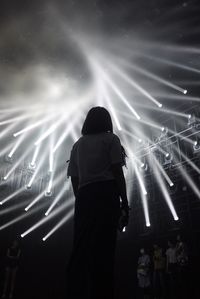 Rear view of silhouette man and woman standing at music concert