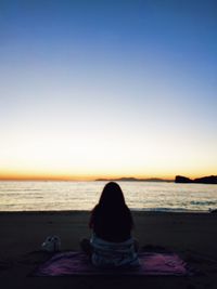 Rear view of woman sitting on beach