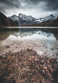 Scenic view of lake by snowcapped mountains against sky