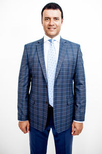 Portrait of confident smiling businessman wearing suit standing against white background