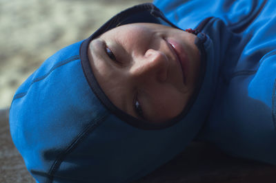Portrait of a woman in hood-clothing smiling and looking at camera at the seashore