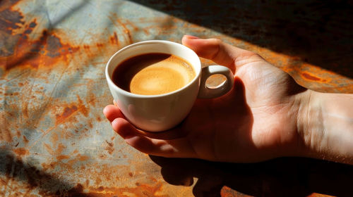 Cropped hand holding coffee on table