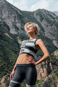 Smiling young woman looking away against mountains