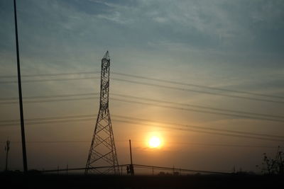 Low angle view of silhouette electricity pylon against sky during sunset