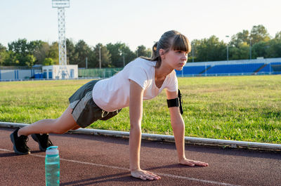 Full length of young woman exercising at running track