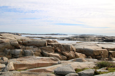 Scenic view of rocks on shore against sky