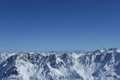 Scenic view of snowcapped mountains against clear blue sky