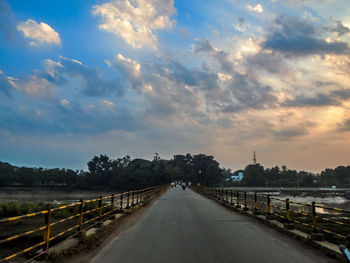 Road amidst trees against sky in city