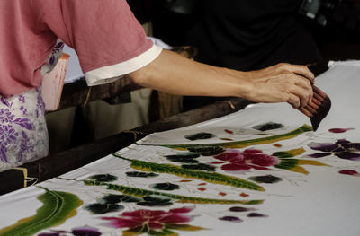 Cropped image of hand printing design on fabric at workshop