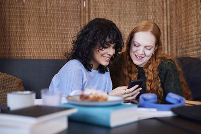 Smiling young women looking at social media on cell phone