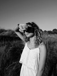 Young woman standing on field against clear sky