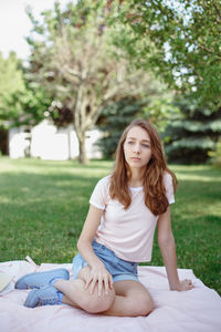 Young woman sitting on grass against plants
