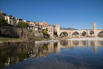 Arch bridge over buildings against blue sky