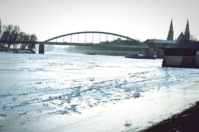 Bridge over river in city against sky