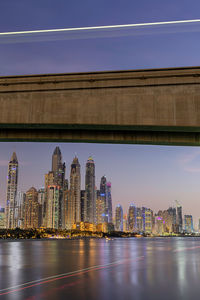 Bridge against illuminated buildings in city against sky
