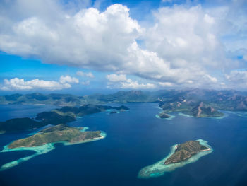 Aerial view of sea and mountains against cloudy sky