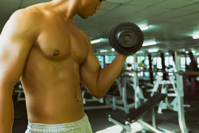 Midsection of shirtless man holding mobile phone