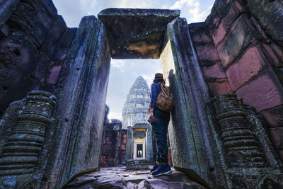 A tourist looking at ancient architecture and sculpture on vacation trip in pimai , thailand