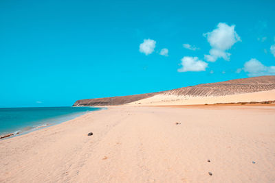 Scenic view of beach against blue sky