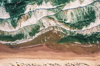 Aerial view of waves in sea during sunny day