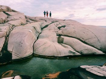 People on rock formation against sky