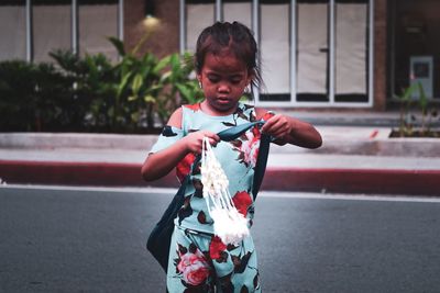 Boy holding umbrella while standing on road in city