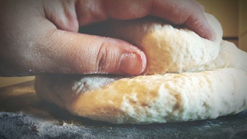 Cropped hand of woman kneading dough on table