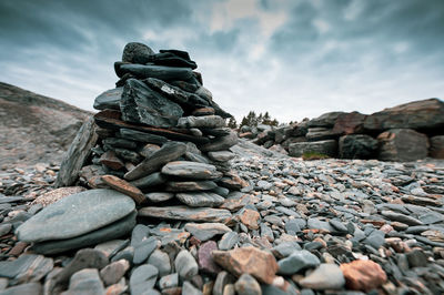 Stack of stones on rock against sky