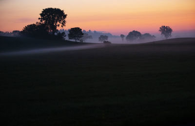 Dawn's early light illuminates morning ground fog on farm land